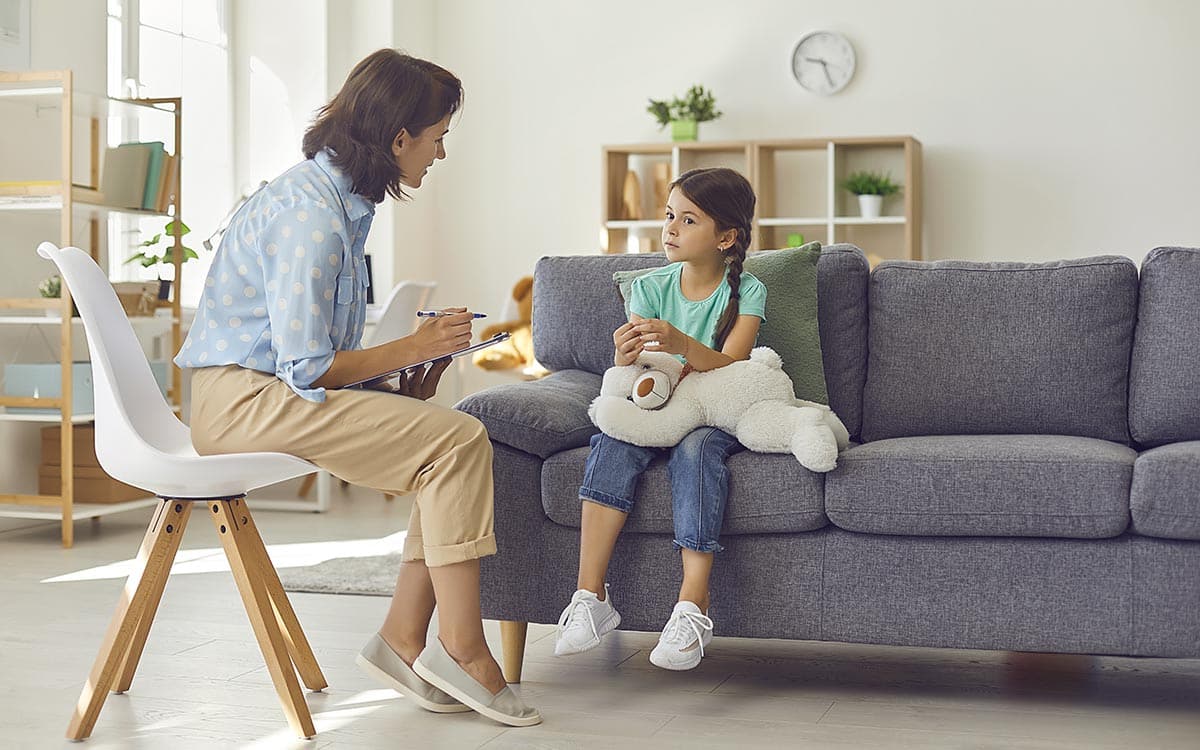 Female child psychologist working with a little preschool girl in a bright office.